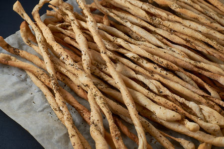 Traditional Italian snack, bread - grissini. On a dark stone table, background with free text space.