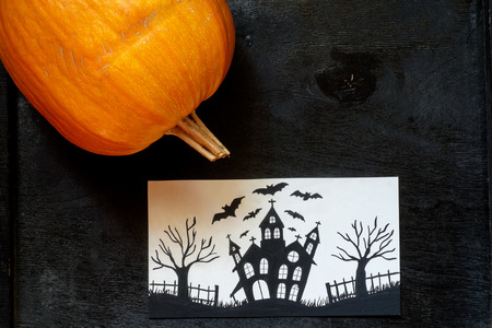 Halloween pumpkin on a black wooden background with a cardの写真素材