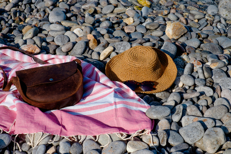 Straw hat, sunglasses, towel, bag on a background seascape with a pebble beachの写真素材