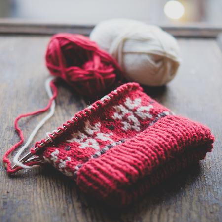 Unfinished knitted cap on knitting needles on a wooden backgroundの写真素材