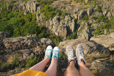 Photo of female and male legs in gumshoes on the background of the canyonの写真素材