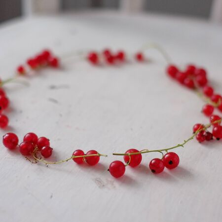A wreath of fresh cherries on a branch and a black currant. Summer festive composition of berries on a wooden table. Shallow Depth of Fieldの写真素材