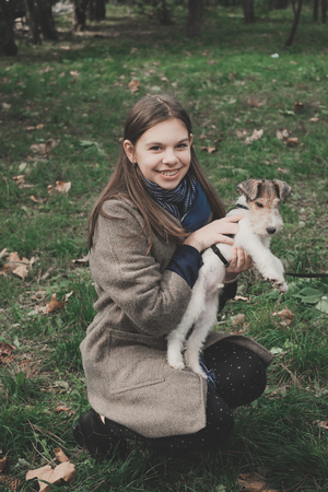 Girl playing with a dog fox terrier. Outdoorの写真素材