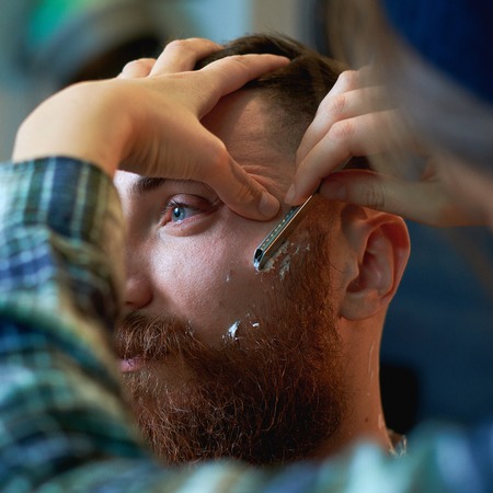 Close up of a hairdressers work for an attractive young blond man at the barber shop. He is doing...