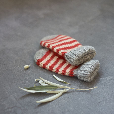 Mitten gray with strips of stripes with a pattern on a gray background closeup.の写真素材
