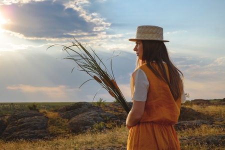 a woman in a straw hat resting near a haystackの写真素材