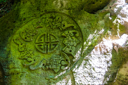 Buddhist symbol overgrown with moss rock carved Buddhist monks in Indiaの写真素材