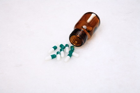 medicine pills pouring out of orange bottle on a white marble. selective focusの写真素材