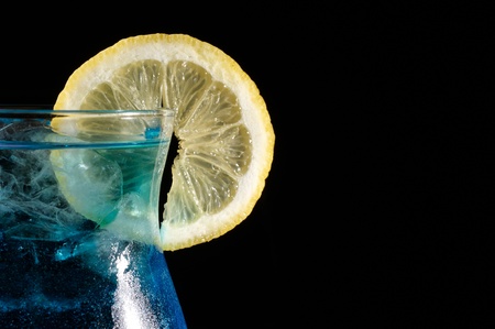 close-up of blue curacao cocktail with slice of lemon on a black backgroundの写真素材
