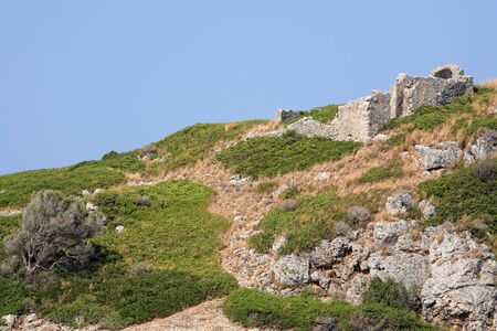 old ruins on the top of a small rock hill filled with grassの写真素材