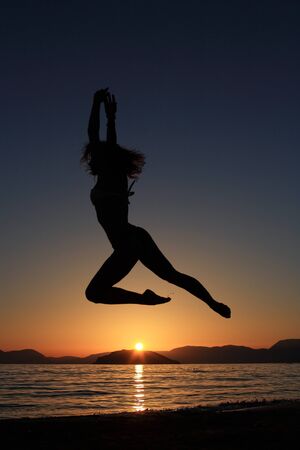 sunset and silhouette of a beautiful dancer in the beachの写真素材