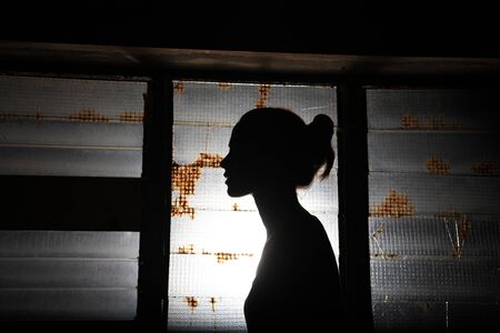 silhouette of a beautiful girl in front of an old windowの写真素材