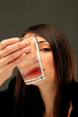 girl holding a glass of water that makes distortion of her mouth