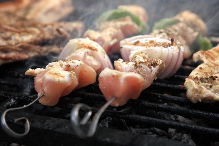 chicken meat skewers grilling on a grid over hot coals in a barbecueの写真素材