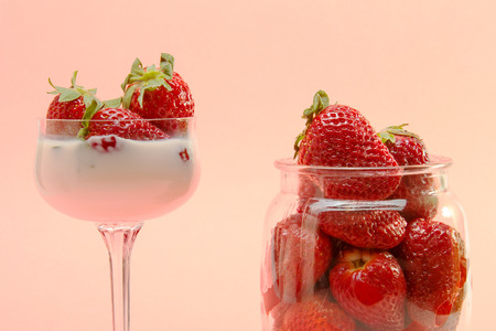 fresh strawberries on a glass filled with cream and a glass pot の写真素材