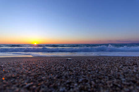 stuning sunset view with beautiful colors from a rocky beach in a greek islandの写真素材