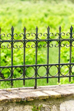 black iron fence with design on the top of a stone wallの写真素材