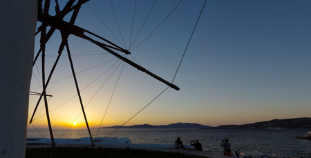 silhouette of windmill and people taking photos at the sunset in mykonos island,Greeceの写真素材
