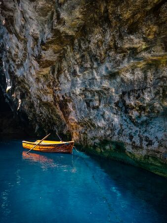 small boat inside a cave lake with blue water in kefallonia greeceの写真素材