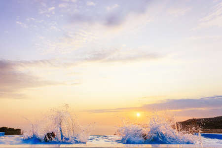 kids jump in the pool with sunset and beautiful view of a summer resortの写真素材