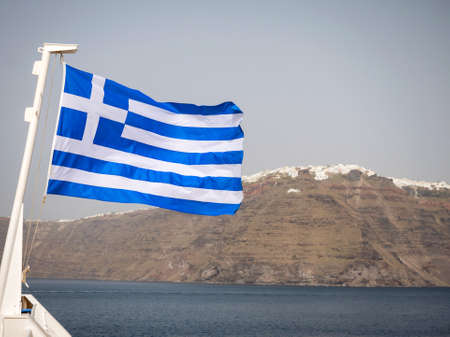 The Greek flag with Santorini island in the backgroundの写真素材