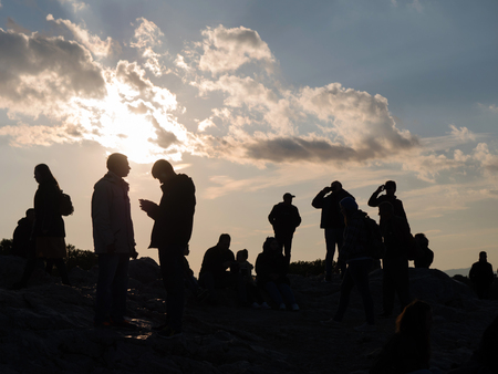 ATHENS, GREECE - JANUARY 2,2017: Silhouette of people against a cloudy sky with sun in Areopagus hill near Acropolis in Athens,Greeceの写真素材