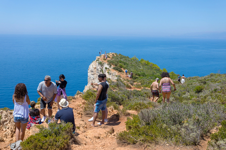 ZAKYNTHOS, GREECE - JULY 21, 2018: Tourists walk at a rough cliff to take photos of the famous beach with an old shipwreck in the island of Zakynthos in Greeceのeditorial素材
