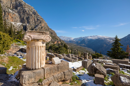 Ruins of Delphi archaeological site with snow in a winter day with sunの写真素材