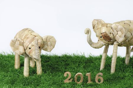 Happy New Year 2016 on green grass concept, elephant rattan and wood number idea