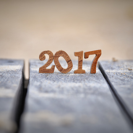 Wood number 2017 on plank and sand background, happy new year concept and happy summer holiday idea
