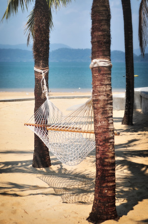 White hammock on tropical beach background, happy summer holiday conceptの写真素材