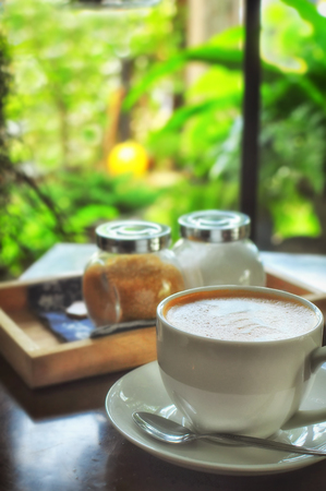 Cup of coffee with brown sugar on table and window backgroundの写真素材
