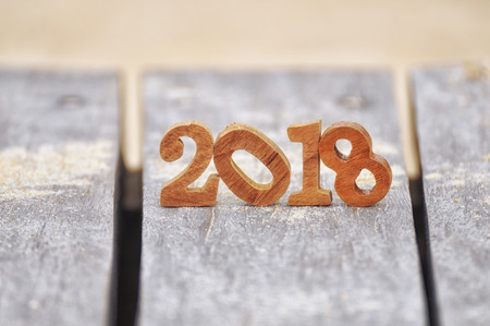 Wood number 2018 on plank and sand background, happy new year concept and happy summer holiday idea