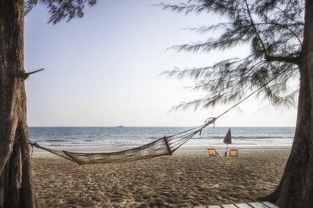 Hammock and two deckchair canvas on sand on tropical beach background, happy summer holiday conceptの写真素材
