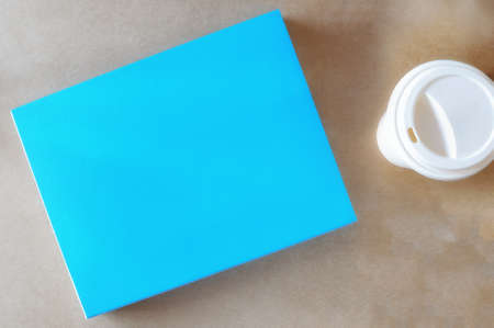 Blank blue book with cup of coffee on brown background, input your text ideaの写真素材