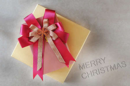 Top view of gift box with red ribbon and merry christmas words on brown background, holiday and...