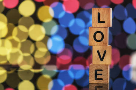 Love word on wooden cube on colorful bokeh background, holiday and event concept and valentine ideaの写真素材