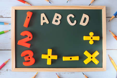 Alphabet letters and number with math symbol on blackboard with coloured pencil, education concept and back to school ideaの写真素材