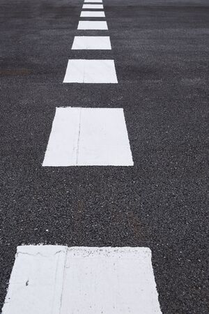 Closeup asphalt road with marking lines for giving directions, traffic lines conceptの写真素材