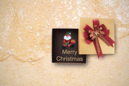 Merry Christmas gift box with Santa Claus on tropical beach background