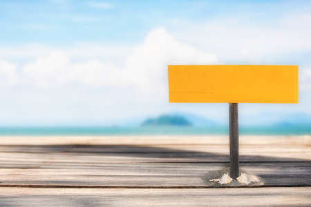 Blank wooden sign on sand on tropical beach background