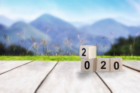Wood cube number 2020 on plank and mountain landscape view background, happy new year concept and happy holiday ideaの写真素材