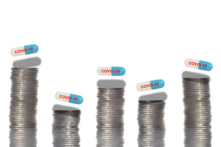 Covid-19 drug capsule on coins layout and stack in w-shaped recession with reflection on white...