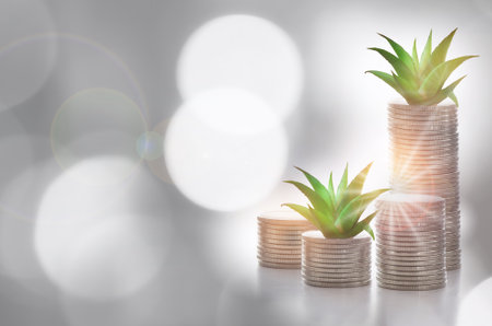 Stack of coins with succulents plant glowing on abstract background. Saving with return on investment concept and sustainable economic growth ideaの写真素材