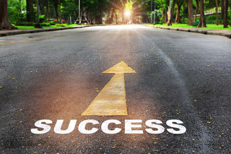Success word written on the road with arrow on nature background with sunlight. Business planning concept and new year beginning success ideaの写真素材
