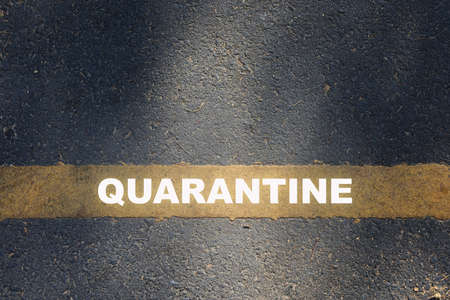 Quarantine written on yellow line on asphalt road. Coronavirus covid-19 outbreak concept and new...