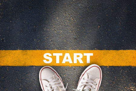 Start written on yellow line on asphalt road with sport shoe. Business development challenge concept and beginning success ideaの写真素材