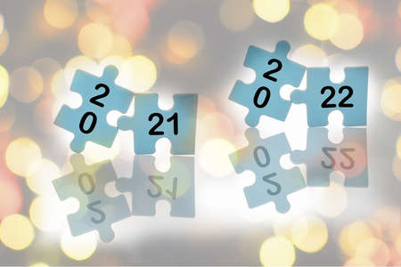 New year 2021 and 2022 on blue puzzle with reflection on abstract background, business success with...