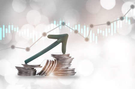 Green arrow upward on stack of coins and growth graph on bokeh background. Economic recovery concept and return on investment ROI ideaの写真素材