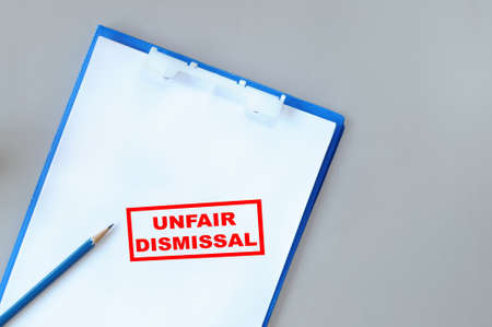 Unfair dismissal written on notepad with paper and pencil on grey background. Economic recession concept and unemployment ideaの写真素材